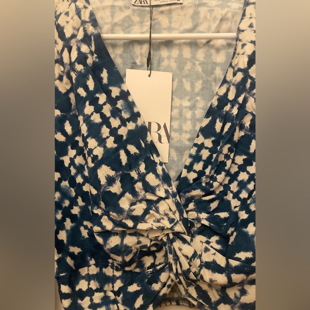 Zara Short top with knotted V-neckline, long sleeves, and flared cuffs.